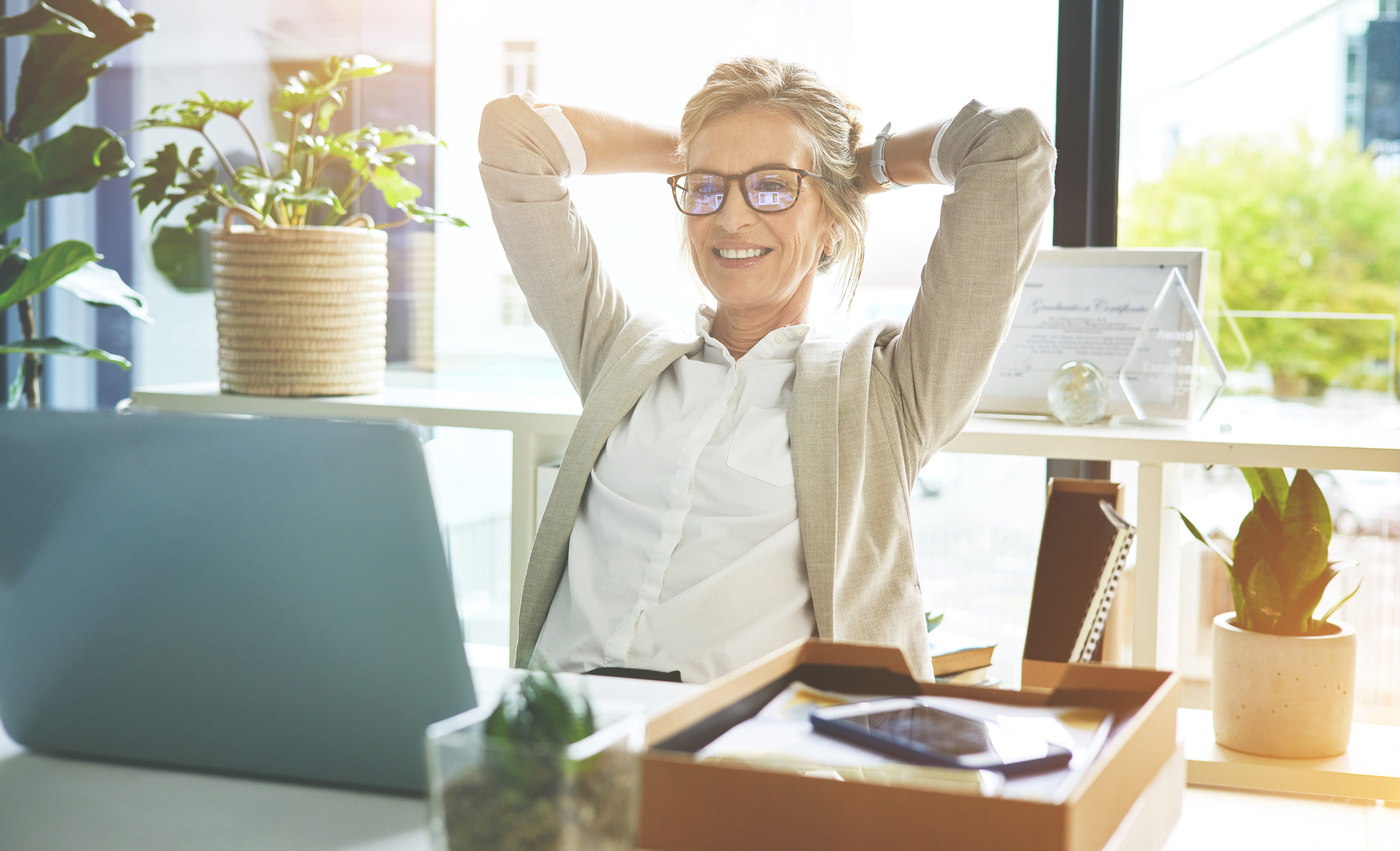  Business woman feeling accomplished and enjoying a relaxing break to stretch with hands behind her head in an office.